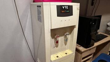 A water dispenser with a VTE label, a computer, and a blue chair.