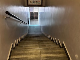 Una escalera de madera con barandillas de metal que lleva a una puerta con un ventanal encima.