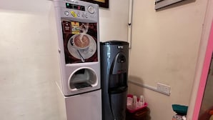 Eine Küchenzeile mit Kaffeemaschine, Wasserspender und Mülleimer.