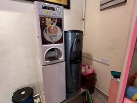 Una kitchenette con cafetera, dispensador de agua y un basurero.
