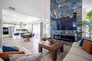 A modern living room with a flat-screen TV mounted on a blue marble wall, a wooden coffee table, and a sofa with cushions. - 3-bedroom house in fabulous Las Vegas (Las Vegas)
