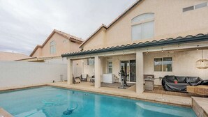 En swimmingpool med en overdækket patio, udendørs møbler og træningsudstyr.