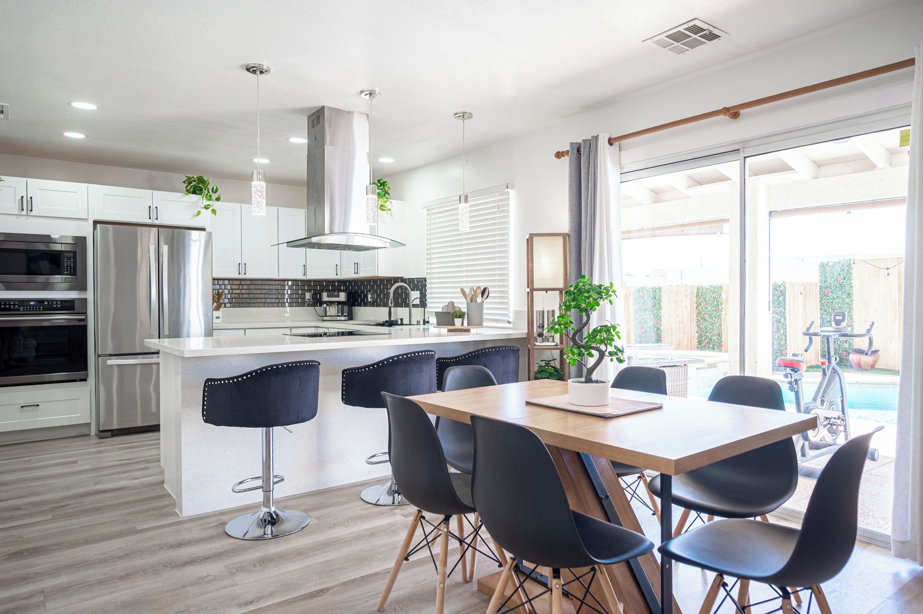 A modern kitchen with white cabinets, stainless steel appliances, and a central island with bar stools.