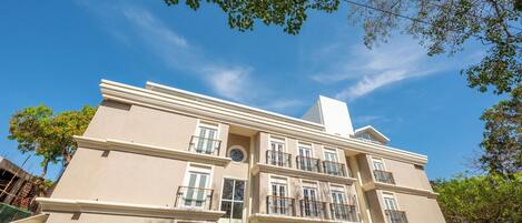A multi-story building with a symmetrical facade, multiple balconies, and a central entrance.