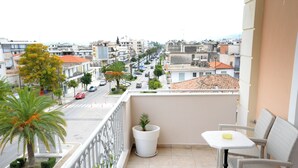A balcony with a view of a city street, a potted plant, and a small table with a chair. - Leonidas View (Sparta)