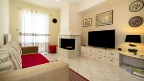 A living room with a fireplace, a television, and a sofa. - Leonidas View (Sparta)