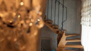 A wooden staircase with a metal railing, a radiator, and a white fluffy object on the floor.