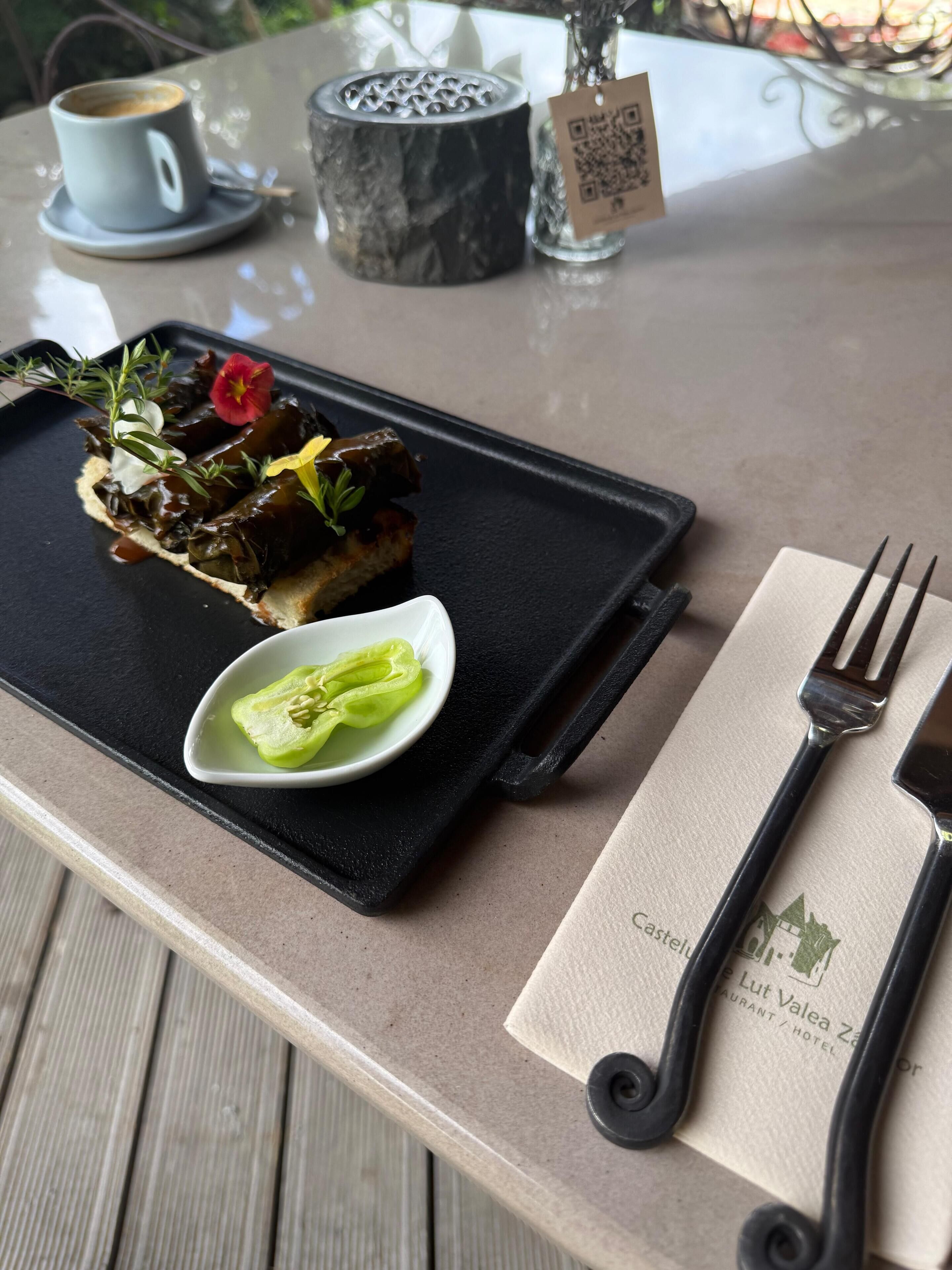 A dessert tray with a slice of cake, a small bowl of green vegetable, and a cup of coffee on a table.