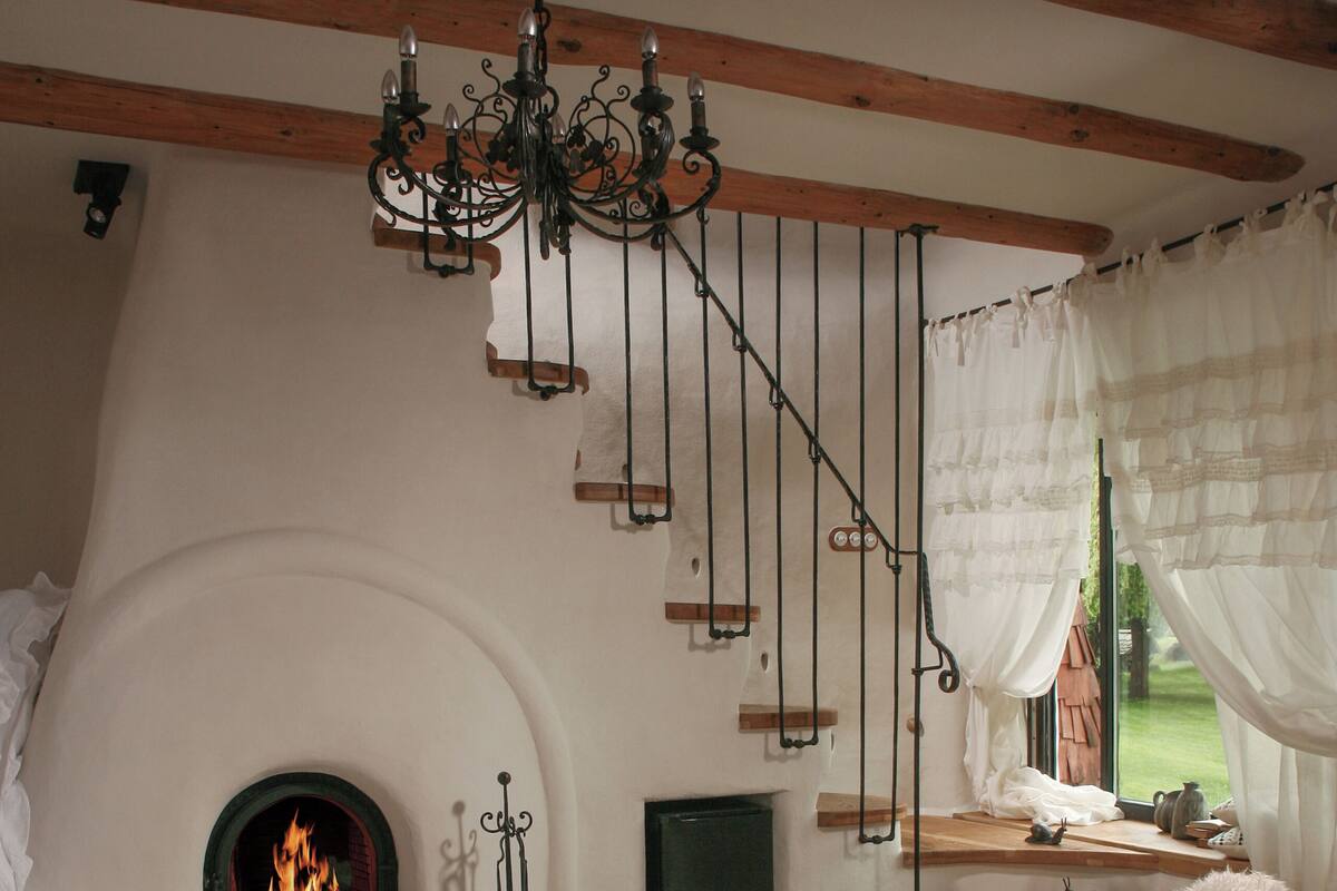 A cozy room with a fireplace, wooden beams, and two fluffy chairs.