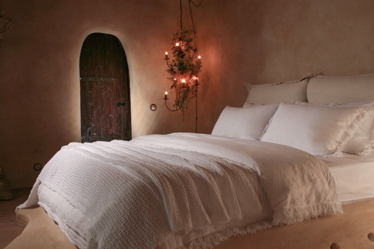 Une chambre confortable avec un lit au design original, une porte en bois et un lustre décoratif.