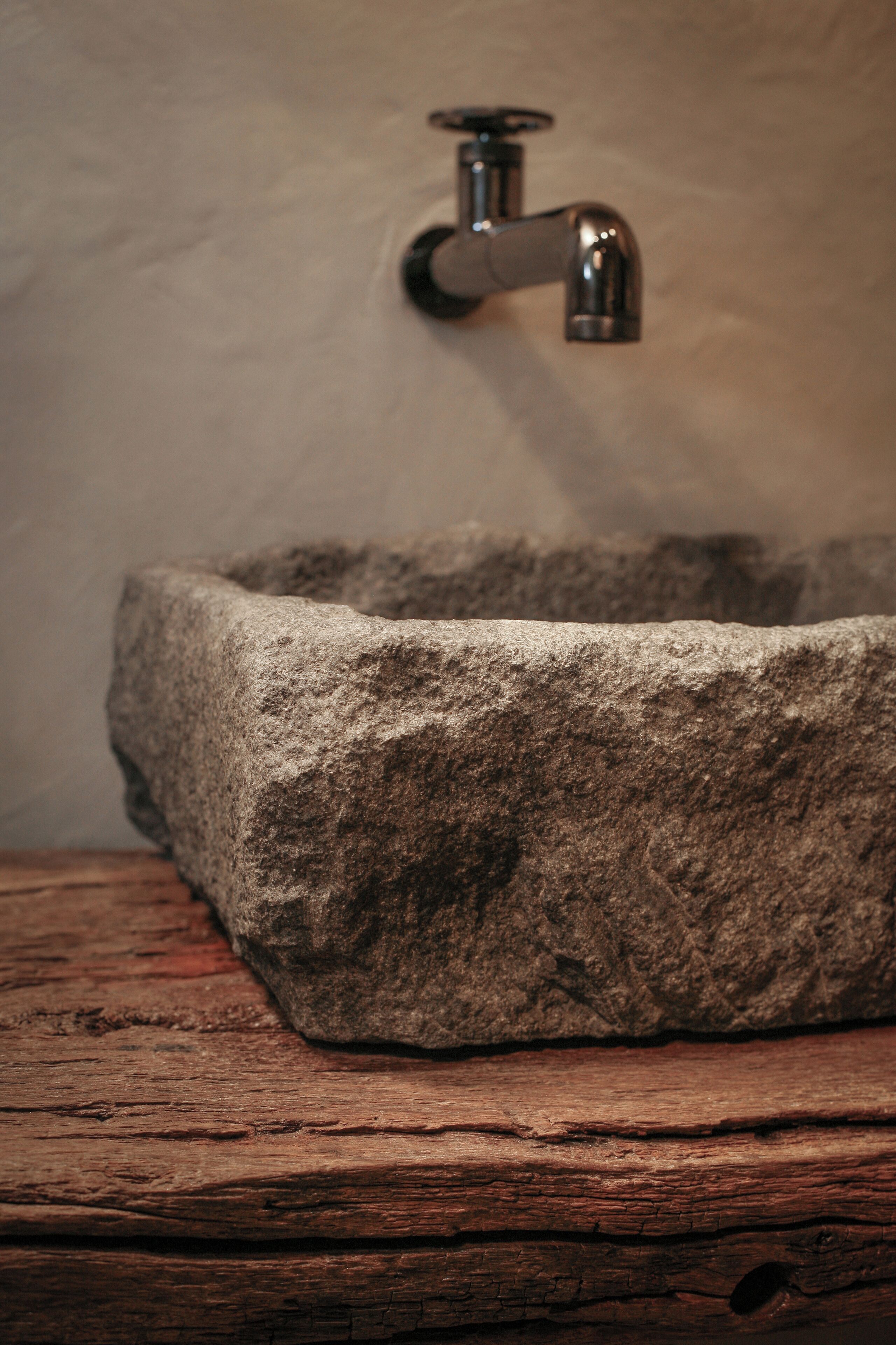 A stone basin with a faucet mounted on a wall.