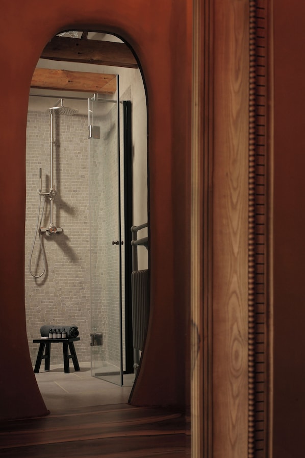 Un baño moderno con cabina de ducha de vidrio, un banco de madera y suelo de baldosas.