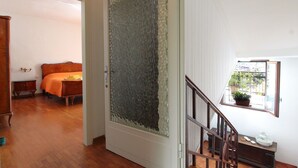 Una habitación con una cama de madera, una mesita de noche pequeña y una ventana con vistas a la vegetación.