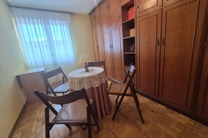 A dining area with a round table, four chairs, wooden cabinets, and a window with sheer curtains. - 213A by R2R Consulting Maximino Apartment (Villaviciosa)