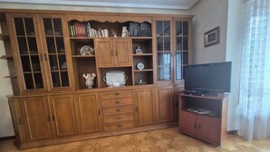 A wooden cabinet with glass doors, a flat-screen TV, and a patterned floor. - 213A by R2R Consulting Maximino Apartment (Villaviciosa)