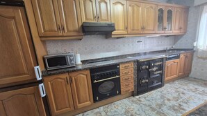 A kitchen with wooden cabinets, a microwave, an oven, and a dishwasher. - 213A by R2R Consulting Maximino Apartment (Villaviciosa)