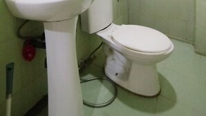 Un bany amb un envàs de rentapeus, vàter i plat de dutxa.