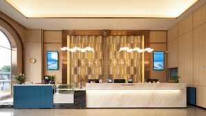 A reception area with a marble counter, multiple computer monitors, and a large digital display. - Yishang Hotel  (Chengmai)