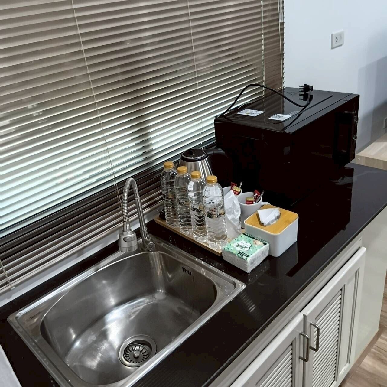 A kitchen with a stainless steel sink, a kettle, and a coffee maker on the counter.