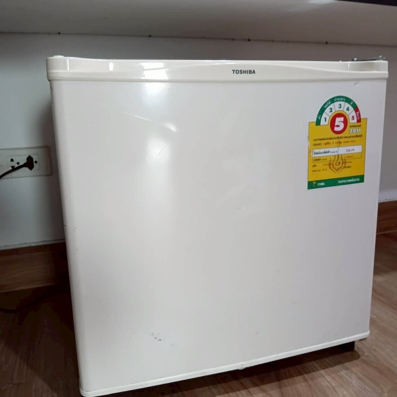A white Toshiba refrigerator with a sticker indicating a 5-star rating from 2011.