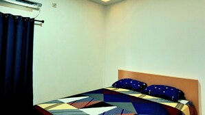 Un dormitorio con cama, cabecera y unidad de aire acondicionado.