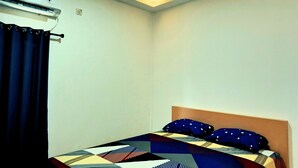 Un dormitorio con cama, cortina, equipo de aire acondicionado e iluminación en el techo.