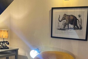 A framed elephant illustration on a wall, a lamp, and a table with a telephone. - Winsford Woodford Cottage - Sleeps 6 - Pets Ok (Winsford)