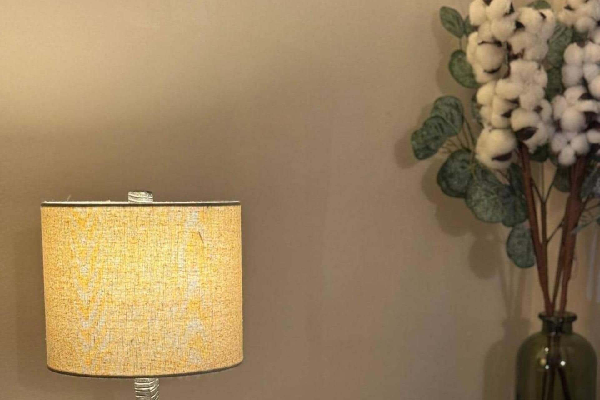 A lamp with a textured fabric shade against a plain wall.
