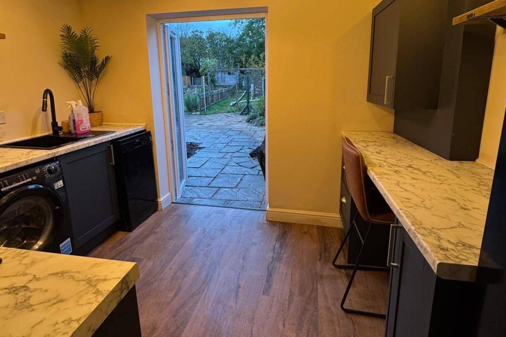 A kitchen with a dishwasher, a sink, and a marble countertop.