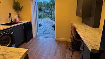 A kitchen with a dishwasher, a sink, and a marble countertop.