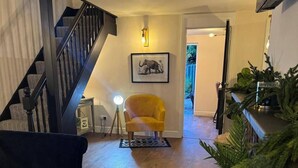 A staircase leading to a second floor, a yellow armchair, a framed elephant picture, and a plant shelf. - Winsford Woodford Cottage - Sleeps 6 - Pets Ok (Winsford)