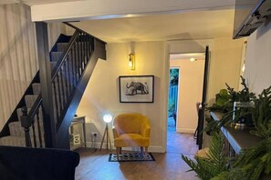 A staircase leading to a second floor, a yellow armchair, a framed elephant picture, and a plant on a shelf. - Winsford Woodford Cottage - Sleeps 6 - Pets Ok (Winsford)