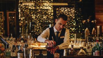 A bartender preparing a drink at a bar with various bottles and glasses.