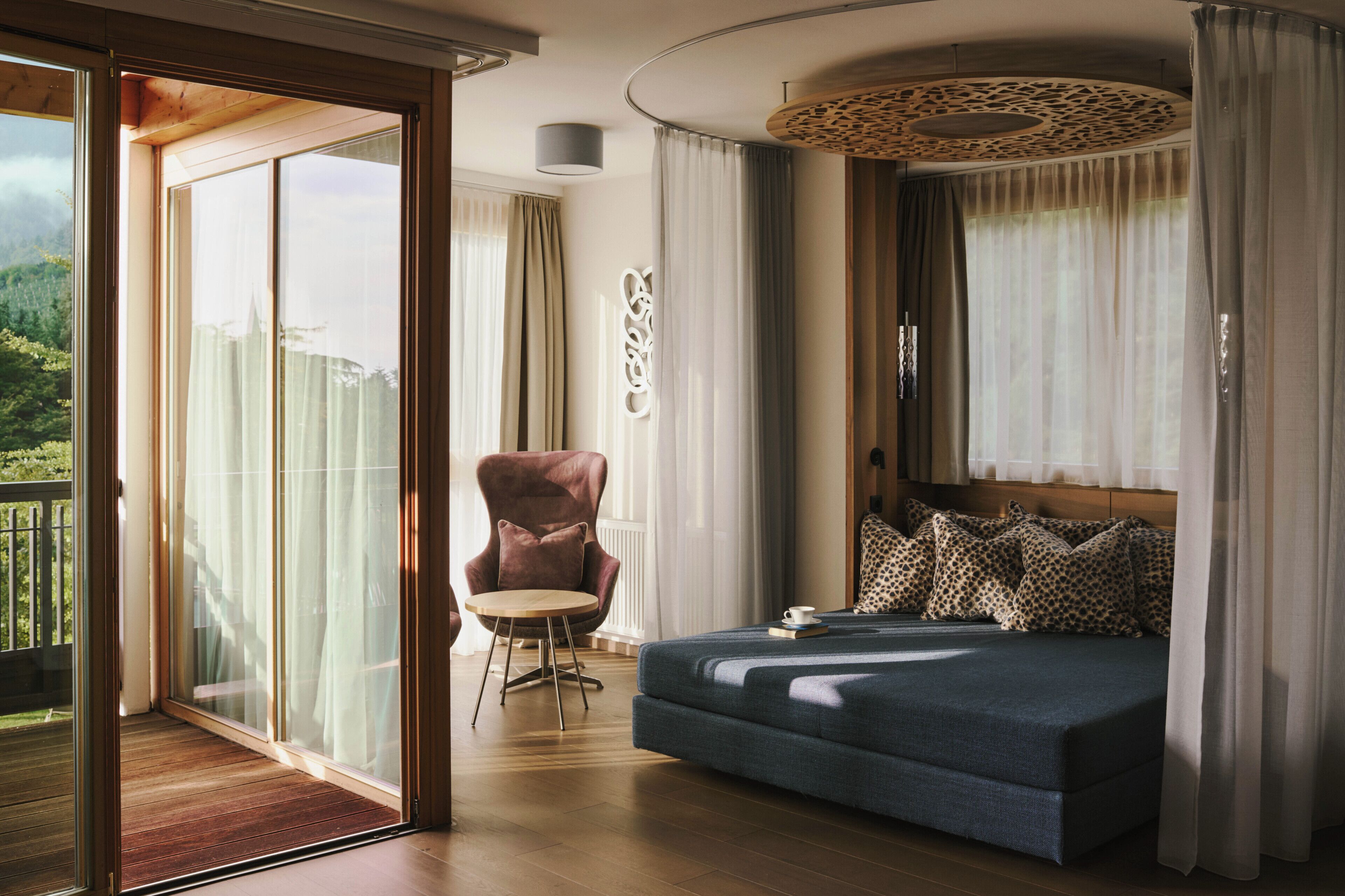 Un dormitorio con una cama grande, una silla y vistas al exterior.