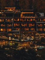 A multi-story hotel with balconies, a swimming pool, and outdoor seating areas.