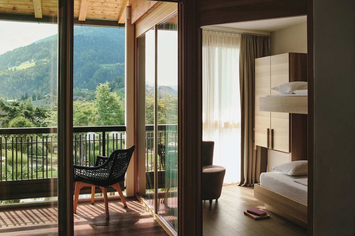 Uma varanda com uma cadeira, um sofá e uma cama beliche com vista para uma área arborizada.