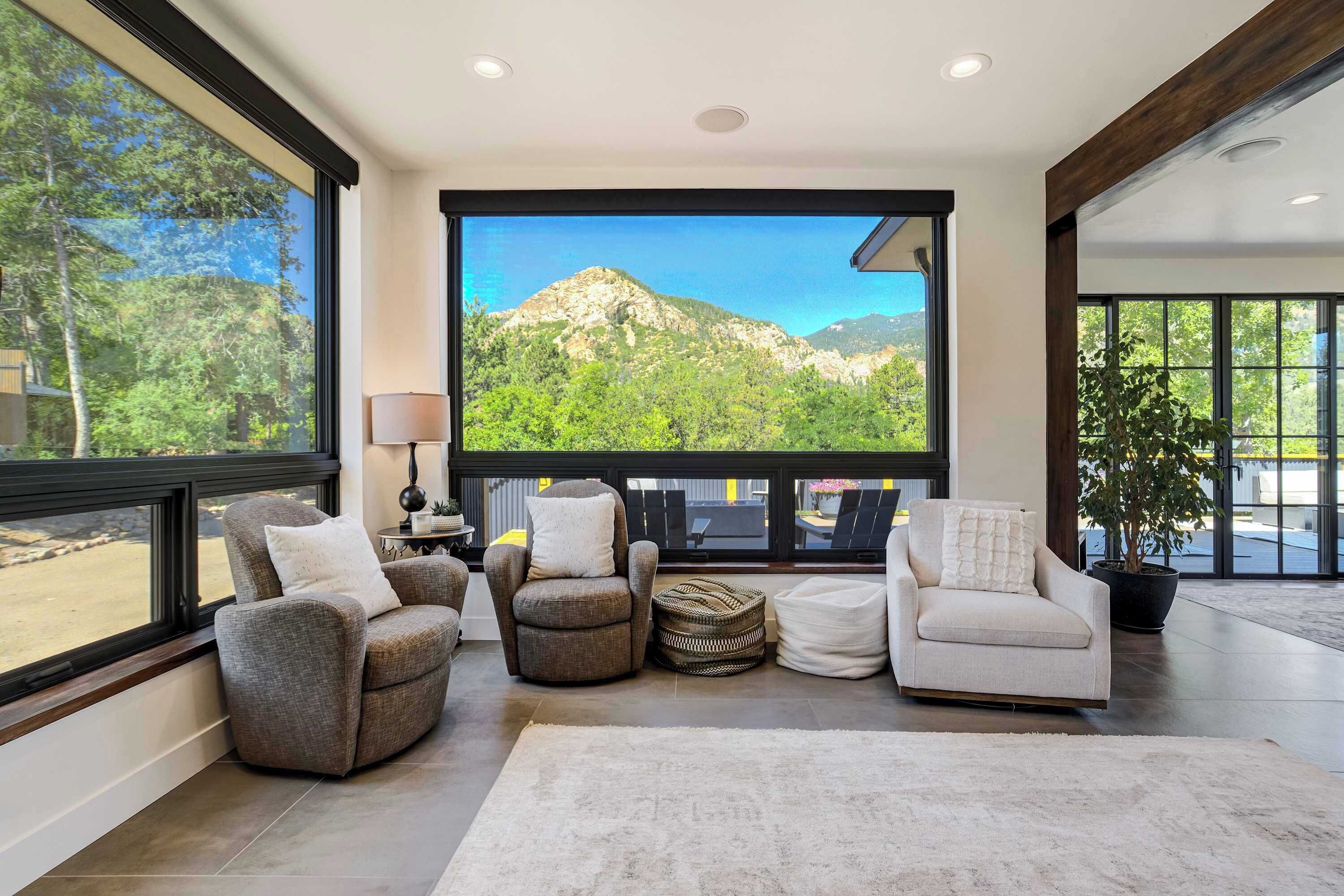 A spacious living room with large windows, a fireplace, and a view of mountains.