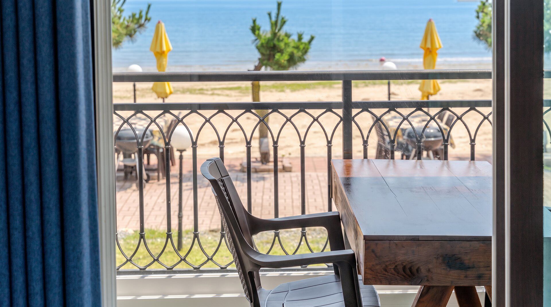 Un balcón con vista a la playa, una mesa y sillas.