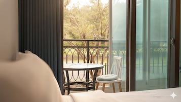 A hotel room with a balcony, a round table, a chair, and a bed.