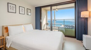 A hotel room with a bed, a view of the sea, and a balcony with a grill. - The Seaside Taean (Taean)