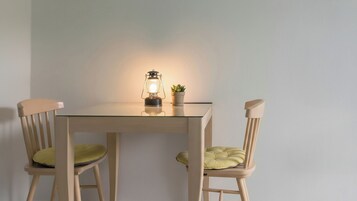 Una mesa con dos sillas, una lámpara de mesa y una pequeña planta en maceta.