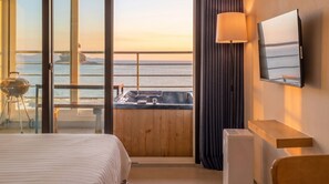 A hotel room with a bed, a desk, a chair, a TV, a lamp, and a view of the sea. - The Seaside Taean (Taean)