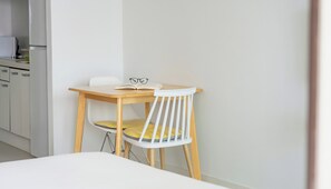 A small, neatly arranged room with a single bed, a wooden table, and a white chair. - The Seaside Taean (Taean)