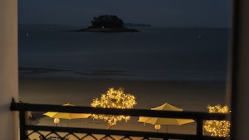 Vista de una playa con una isla distante, sombrillas y luces.