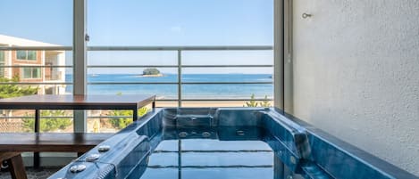 Ein Whirlpool mit Meerblick und ein Balkon mit einem Tisch.