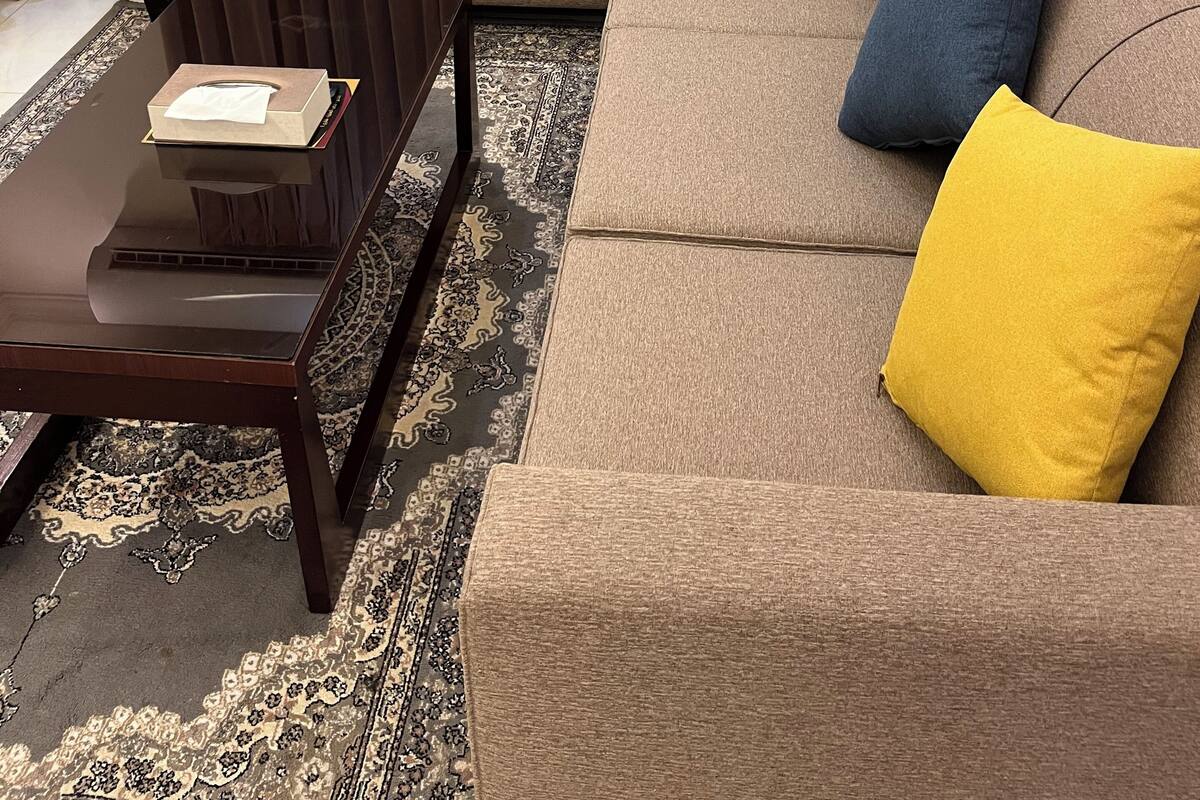 A living room with a sofa, two armchairs, a coffee table, and a small table with a plant.