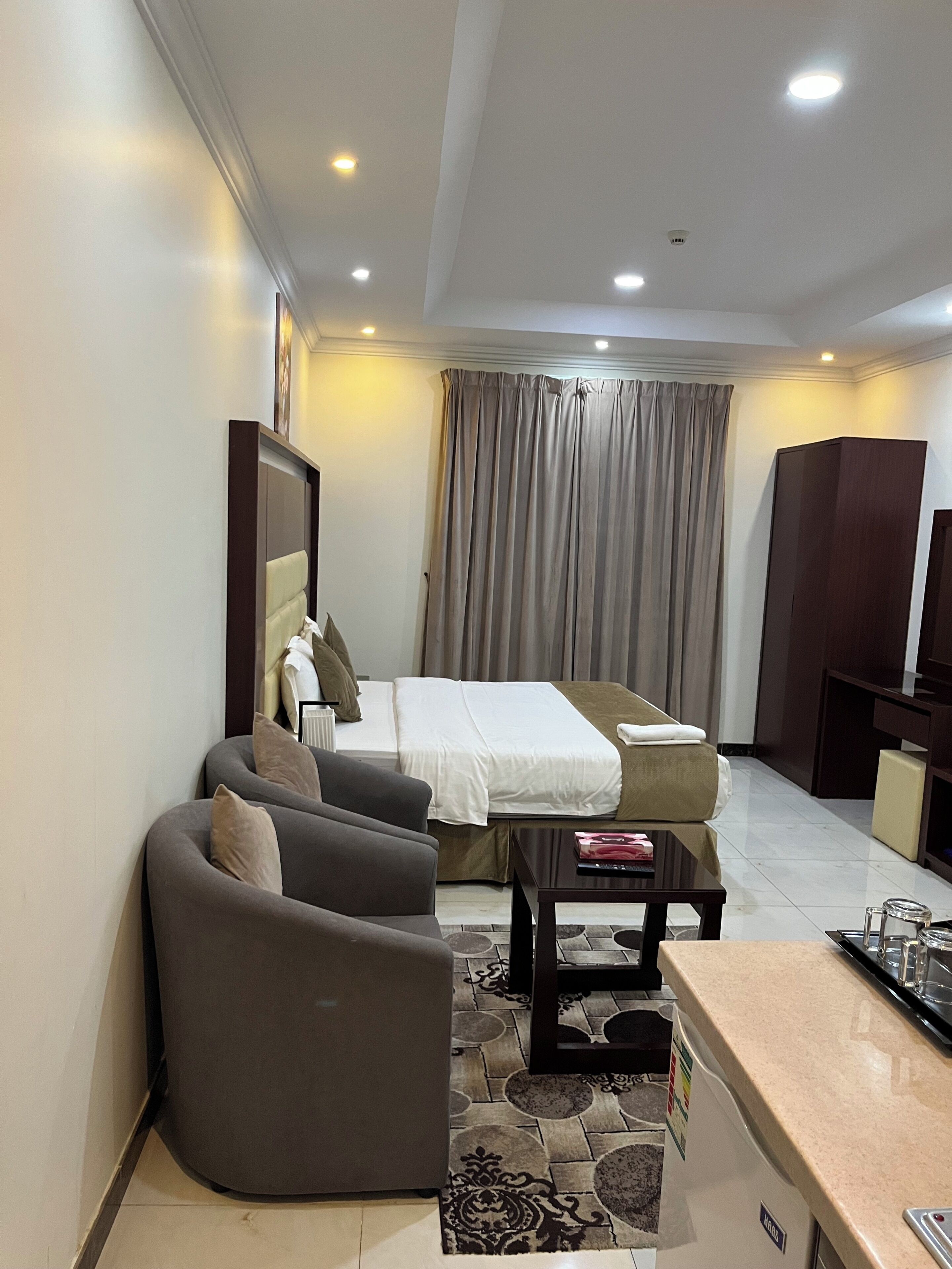 A hotel room with a bed, a sofa, a small table, a TV, and a wardrobe.