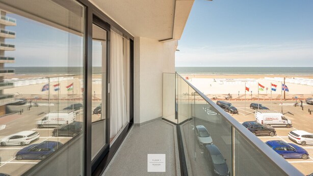 A balcony with a view of a beach, parking area, and flags. - Boulevard Floor, top location and parking incl. (Knokke-Heist)