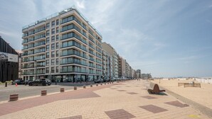 A modern hotel with multiple floors, a paved walkway, and a beachside view. - Boulevard Floor, top location and parking incl. (Knokke-Heist)