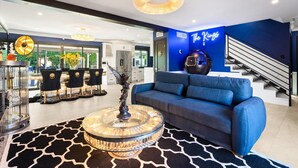 Un soggiorno moderno con un divano blu, un lampadario e un tavolino in vetro decorativo.